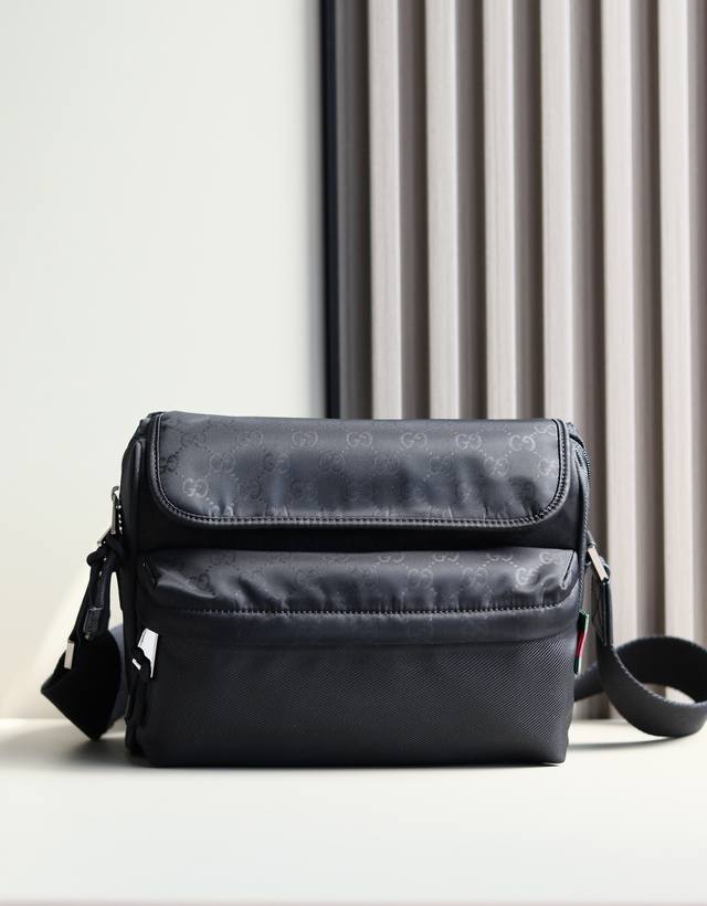 新品 2025早春男士包袋系列，匠心融蕴时尚线条与运动风尚。这款斜挎包以柔软耐用的黑色尼龙材质匠心打造，通体Gg图案彰显精致底色。其他经典细节还包括红绿织带细节