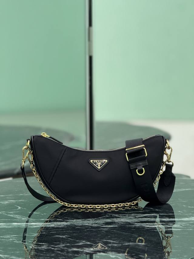 正品级 新品月牙包 这款Re-Nylon手袋采用再生尼龙面料制作，精致而百搭，融合档案库造型与实用的当代风格。半月廓形，搭配可拆卸运动风肩带与优雅的链条手提柄，