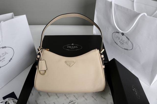 原厂小牛皮 简介： 这款皮革Hobo腋下包设计气质简约，采用进口小牛皮，正面金属三角形珐琅徽标，配有可拆卸皮革肩带，皮质细腻柔软，实用轻便容量空间大，巧妙融合多