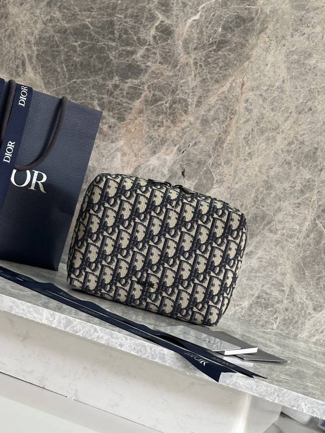 这款旅行手拿包实用又时尚。采用米色和黑色Oblique 印花面料等材质精心制作，正面饰以Dior标志提升格调。缝有三角形衬料的设计，宽大的拉链隔层设有三个插袋和