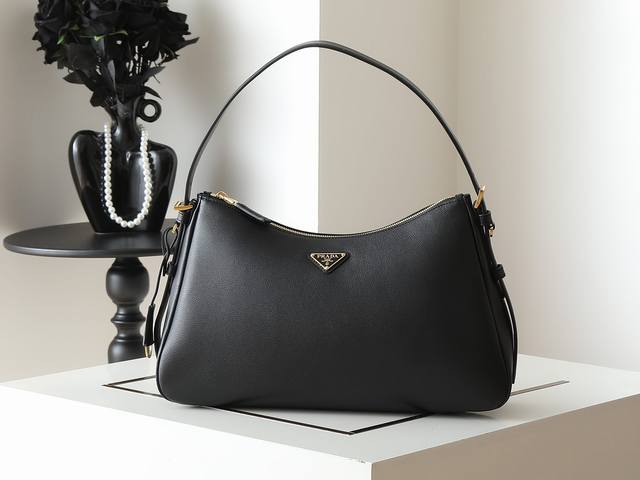 新款Aimee腋下包1Bc228这款皮革Hobo腋下包设计气质简约，采用进口小牛皮，正面金属三角形珐琅徽标，配有可拆卸皮革肩带，皮质细腻柔软，实用轻便容量空间大