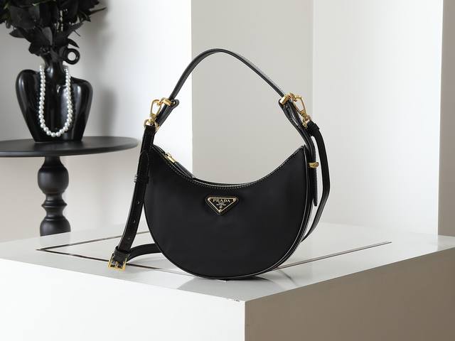 Moon手袋1Bc194双肩带 尼龙面料 这款简约Moon手袋为尼龙面料 亮面牛皮绽现摩登百搭的魅力。弧形包身设计，配有2条长 短可调节肩带，便于随心转换造型。