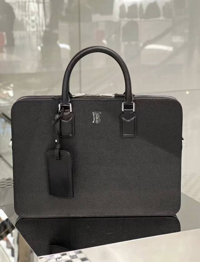 纤巧立挺的设计，选用意大利鞣制粒纹皮革材质打造，装饰镀钯金 Tb 专属标识。 尺寸：27 X 5 X 37.5Cm 顶部轧制皮革提柄 可拆可调式肩背带 1个外侧