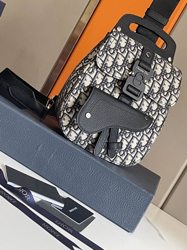 顶级原单 这款 Dio Oblique 黑色牛皮_提花迷你马鞍包小胸包采用标志性的黑色粒面牛皮革细节装饰。正面翻盖采用“Christian Dio”搭扣闭合，搭