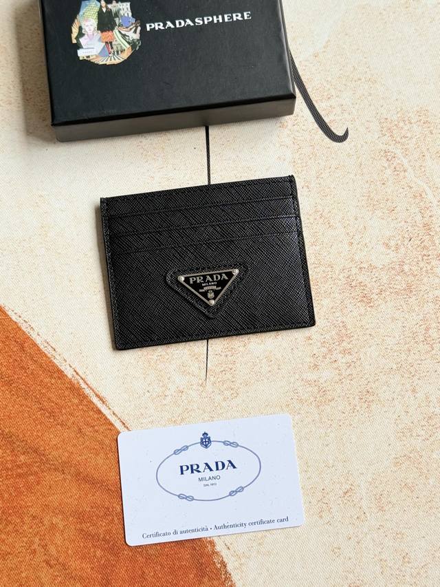 Prada经典款女士卡片夹专柜官网同步，型号1Mc025三角麦 走线做工精湛完美 十字纹牛皮，这款Saffiano皮革卡片夹以标志性的涂珐琅金属贴花装饰，开启奇