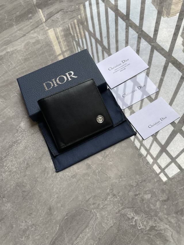 Dior 男士短款钱夹，采用黑色光滑牛皮革精心制作，饰以金属覆层黄铜Cd Button标志。双折款式，搭配黑色头层牛皮，内置1个双层现金隔层，2个票据隔层和8个