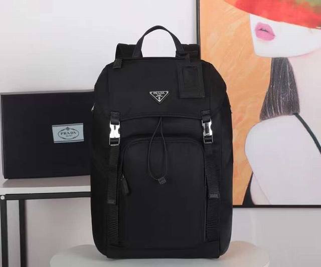 独家首发2Vz135双肩背包这款尼龙背包饰有Saffiano皮革饰边，用创意与科技打造别致格调。多个口袋和科技材质加衬背面颇具设计特色。经典中的新款，时尚又大气