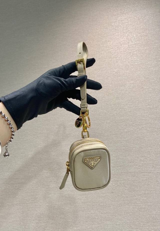 特级版本 迷你小包1Tt200新品这款迷你小袋风格百搭，选用Re-Nylon打造，巧妙融合实用的再生尼龙，可拆卸皮革腕带和镀金色五金配件，又可挂在包上和腰袋上装