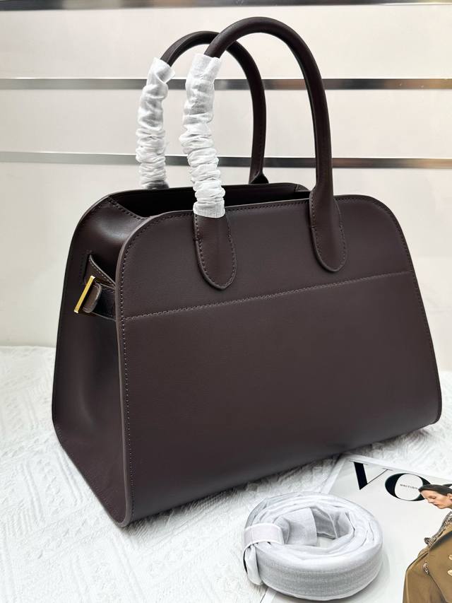 特价 9233平纹咖啡 The Row Margaux 12，演绎极致极简风尚。精选进口小牛皮，细腻柔软的马鞍皮材质，纹理细腻仿若天成，触感柔软且耐磨，每一次触