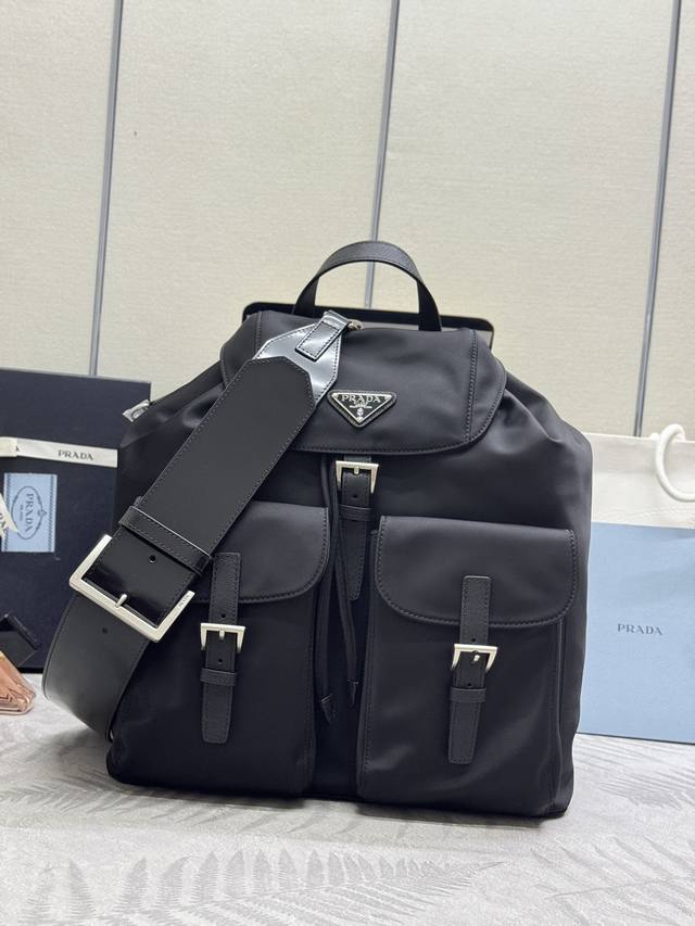 新款双肩背包2Vz110+光面皮肩带复古五金，这款Re-Nylon双肩背包采用经典尼龙面料设计，复古怀旧五金，融合创新实用元素，呈现精致隽永风范。配有一条可拆卸