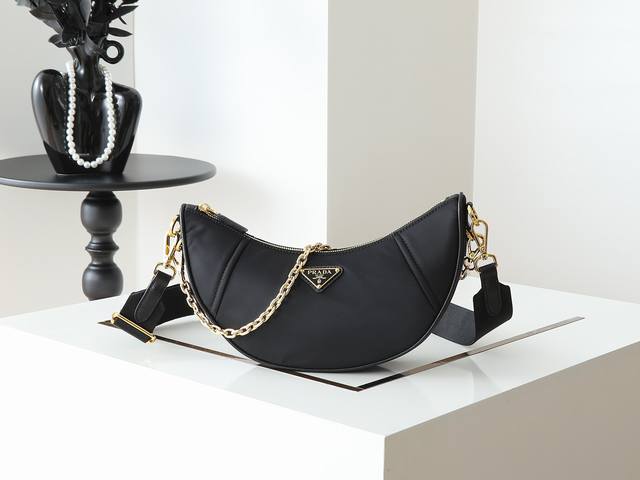 新品月牙包1Bh222多功能这款Re-Nylon手袋采用再生尼龙面料制作，精致而百搭，融合档案库造型与实用的当代风格。半月廓形，搭配可拆卸运动风肩带与优雅的链条