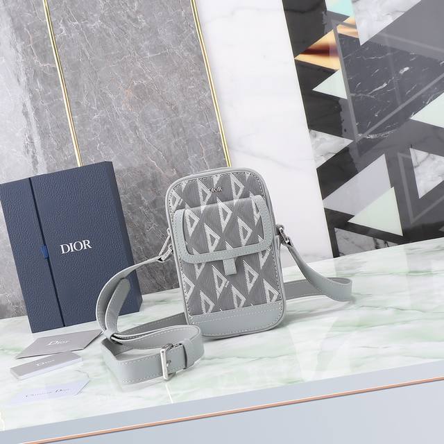 这款 Dior Hit The Road 信使包是本季新品，将现代风格与 Dior 的高订精神融为一体。采用迪奥灰 Cd Diamond 图案帆布和光滑牛皮革精