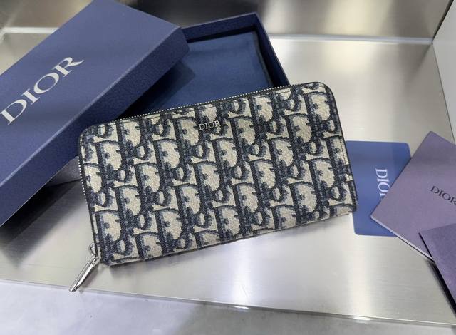 这款长款拉链式钱包低调而不失优雅气质。原单材料精心制作，内部为黑色光滑牛皮革材质。中间的拉链口袋可放置硬币，双层现金隔层和 12 个卡槽提供充足的收纳空间。优雅