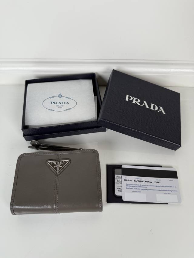 P家灰色油腊牛皮制作短夹，型号1Ml018，按扣开合设计，内设9个卡槽，一个钞票隔层，一个带拉链的零隔层，尺寸12 X 8Cm，尺寸小巧但功能齐全，实用与时尚兼