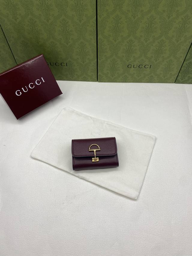 配红盒包装 Gucci延续品牌深厚传承，深化与马术本源的联结。半马衔扣图案化身为开合细节，为多款小皮件增色添彩。这款卡片夹以古驰棕色粒面牛皮革匠心打造，经典元素