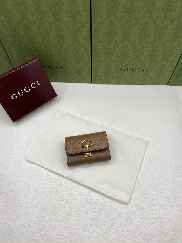 配红盒包装 Gucci延续品牌深厚传承，深化与马术本源的联结。半马衔扣图案化身为开合细节，为多款小皮件增色添彩。这款卡片夹以古驰棕色粒面牛皮革匠心打造，经典元素