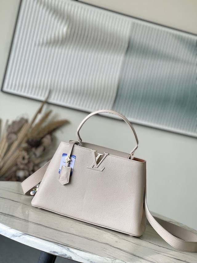 特级原厂皮 M12929 本款Capucines Souple中号手袋令亮泽牛皮革呈现褶皱效果，与耀目金属件碰撞视觉反差。精巧钥匙包延续标志性笔触，可拆卸花卉造