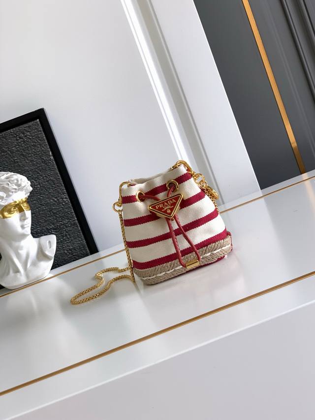 迷你小水桶这款迷你小包崭新诠释经典航海风元素，呈现典雅的夏日质感与精致细节。选用条纹织物打造，底部的设计灵感源自草编鞋，搭配皮革抽绳与精致可拆卸肩带。太可爱了可