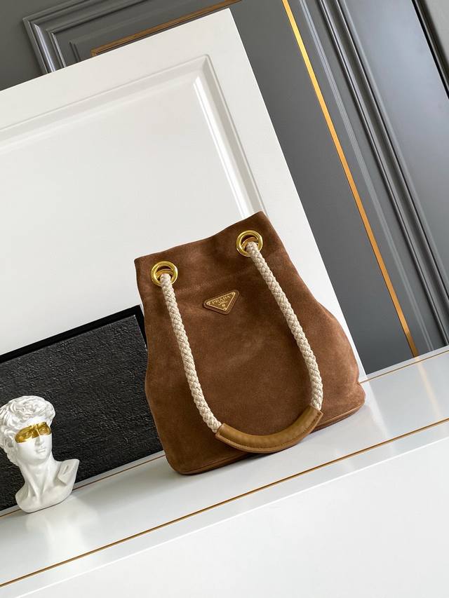 新款水桶包磨砂皮 这款Re-Nylon 手袋的設計采用进口麂皮面料和小牛皮。獨特的組合添上迷人點綴。滑動式繩索手挽凸顯這款手袋的靈活百搭，方便手提或肩背 斜跨，