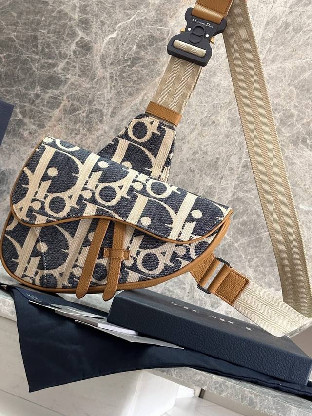 这款马鞍包是 Dior 经典单品。采用酒椰草效果 Oblique 印花牛仔面料等材质精心制作，饰以蓝色提花刺绣，点缀以对比鲜明的米色缝线，全新演绎 Dior 经
