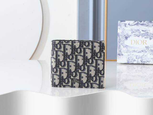 款号027 采用米色和黑色 Oblique 印花面料精心制作，正面饰以金属覆层铜合金Dior 标志，两个扁平隔层和八个卡槽，双折款式，尺寸：11.5Cm-9.5