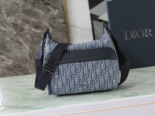 这款Rider Soft水饺包是二零二五秋季男装系列新品，兼具实用功能与时尚设计。采用蓝色Oblique 印花面料等材质精心制作，搭配同色调粒面牛皮革细节提升格