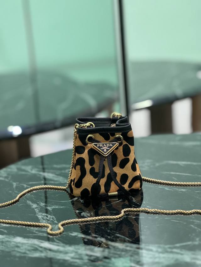 豹纹小水桶 这款Mini小水桶采用进口豹纹印花材质，和涂珐琅金属三角形徽标装饰开合设计。金属铁琏可斜跨。太可爱了 尺寸：长10X高12X底7Cm 款号：1Nr0