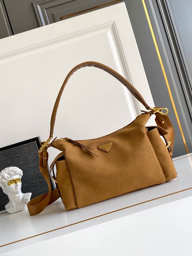 新款麂皮探索包 这款探索包采用进口麂皮，具有柔软的轮廓和多个口袋。轻质实用的Re-Nylon强调了设计的多功能风格，而皮革细节和标志性点缀则反映了P家的手工传统