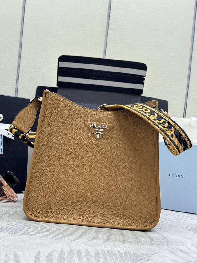 新款织物斜跨包1Bc073 大号Tote包 这款皮革迷你单肩包设计简约。正面金属三角形徽标平添标志性格调。配有可拆卸 调节徽标印花织带，上身效果非常美彰显其现代