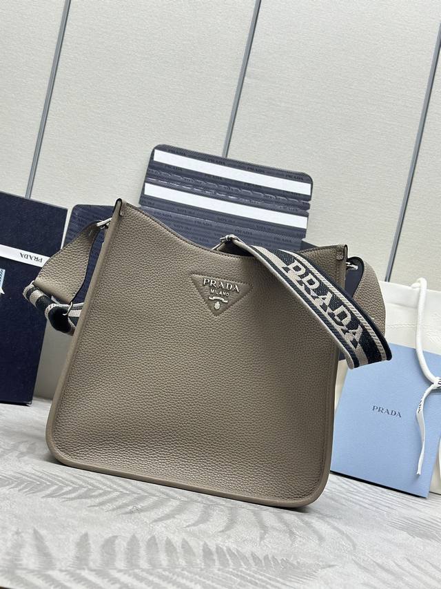 新款织物斜跨包1Bc073 大号Tote包 这款皮革迷你单肩包设计简约。正面金属三角形徽标平添标志性格调。配有可拆卸 调节徽标印花织带，上身效果非常美彰显其现代