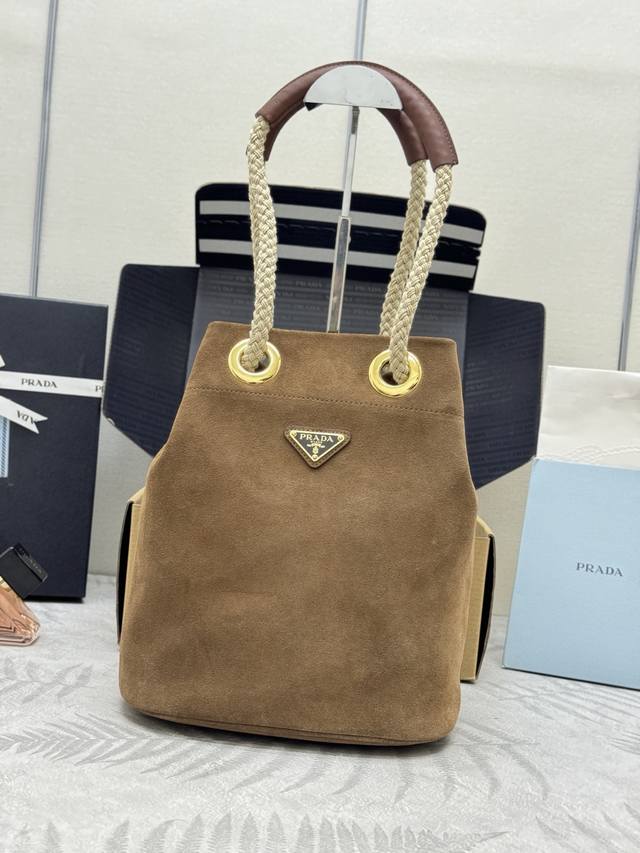 新款磨砂水桶包1Be082麂皮磨砂棕色 这款Re-Nylon 手袋的設計采用进口麂皮面料和小牛皮。獨特的組合添上迷人點綴。滑動式繩索手挽凸顯這款手袋的靈活百搭，