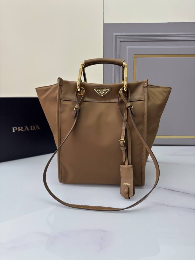 新款托特包1Bg578 这款托特包采用时尚几何造型，融合实用的Re-Nylon再生尼龙材质与精致细节。造型百变，搭配金属与皮革双手提柄，可在手提包与单肩包之间随