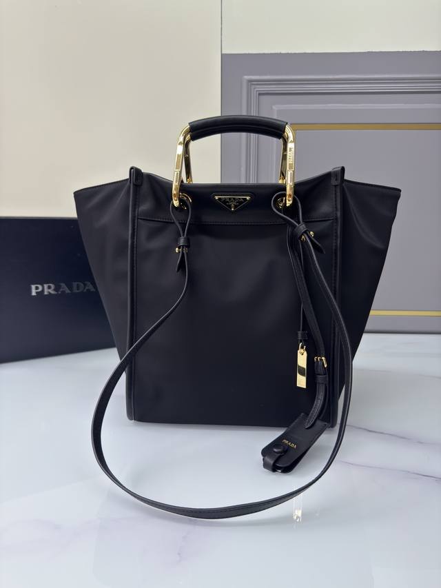 新款托特包1Bg578 这款托特包采用时尚几何造型，融合实用的Re-Nylon再生尼龙材质与精致细节。造型百变，搭配金属与皮革双手提柄，可在手提包与单肩包之间随