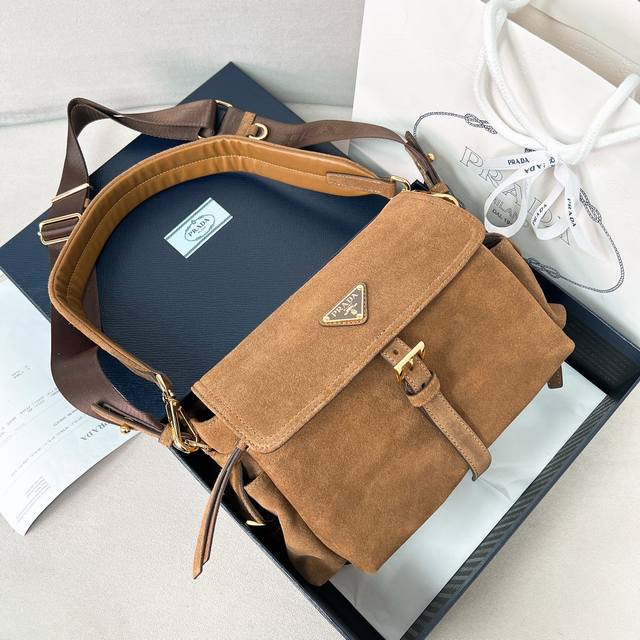 新款邮差包1Bd394麂皮 这款手袋完美融合精致与功能性，采用进口麂皮轮廓柔和，配有多个口袋。轻盈实用的设计结合运动与百搭元素，饰有涂珐琅三角形金属徽标，搭配皮