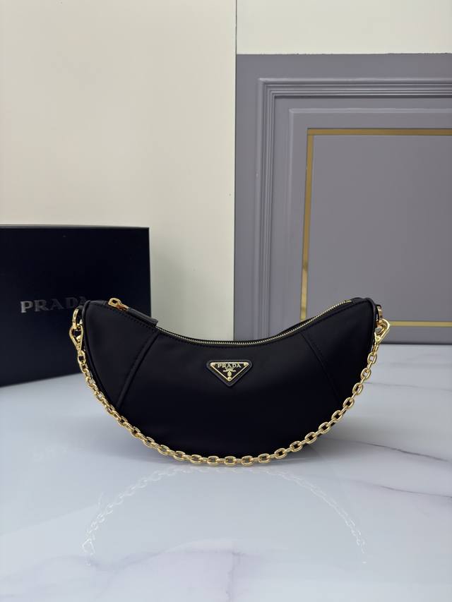 新品月牙包1Bh222多功能 这款Re-Nylon手袋采用再生尼龙面料制作，精致而百搭，融合档案库造型与实用的当代风格。半月廓形，搭配可拆卸运动风肩带与优雅的链