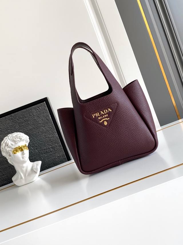 2025最新款菜篮子托特包迷你款 金色五金 这款皮革迷你手袋采用解构廓形，以反向缝线诠释精美设计，打造柔和圆润的时尚造型。正面饰有金属字母徽标，更添轻盈、现代和