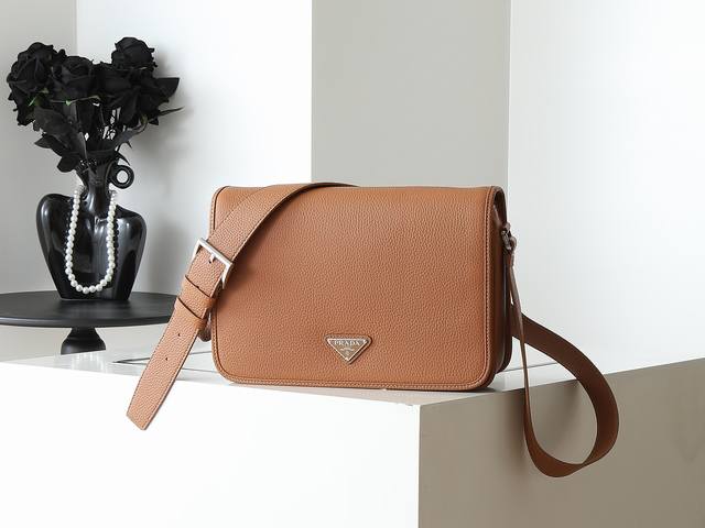 新款邮差包2Vd075 这款精致多功能的单肩包采用流畅设计，由柔软牛皮革制成，具有自然触感的表面。流畅的细节强调了简单的轮廓，可调节皮革肩带，磁扣翻盖设计，上身