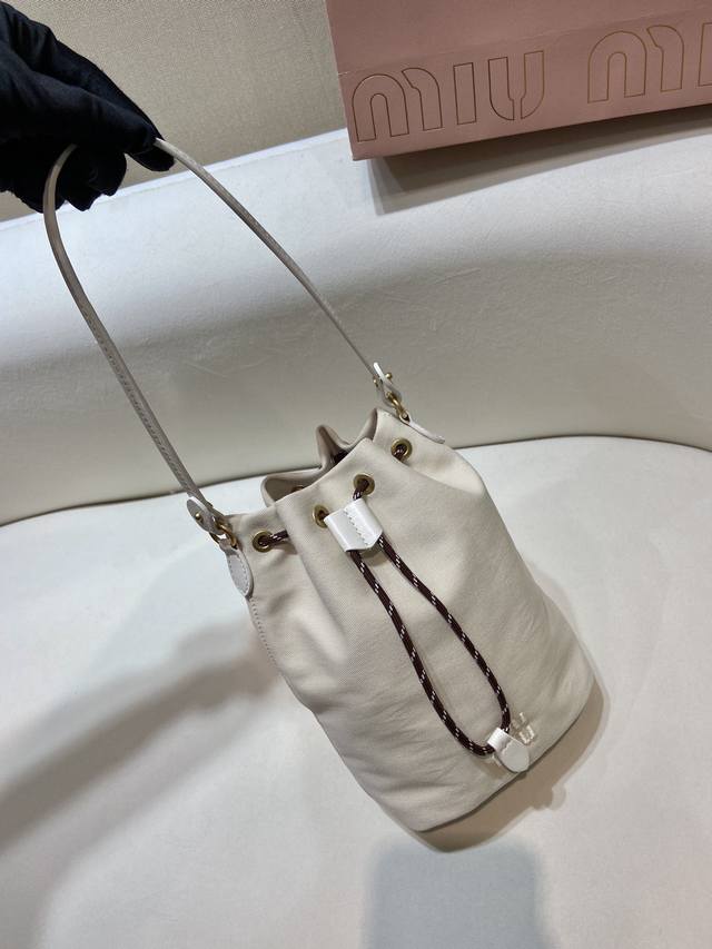 新款水桶包5Nr038 这款水桶包采用华达呢织物与同色系刺绣徽标，赋予了这款小袋百搭特质，双色编织饰带抽绳彰显M永风格本真，编织抽绳开合，皮革手提柄。容量空间大