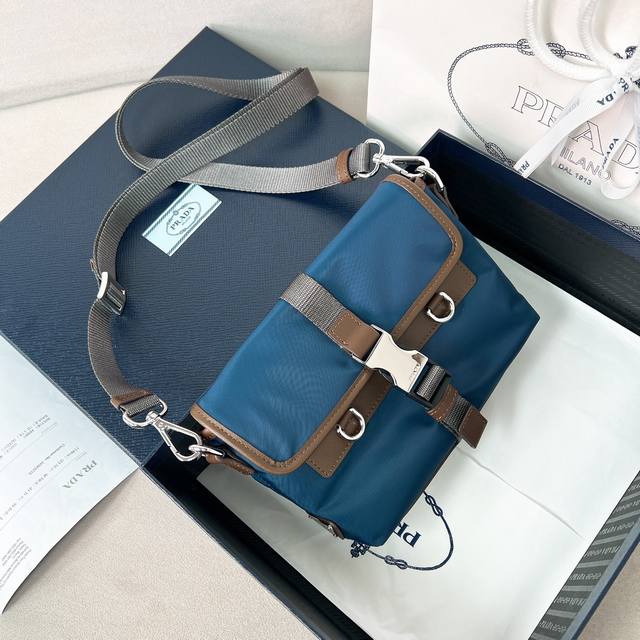 男女士手机包2Zt071拼色尼龙布2025新款牛皮革配尼龙布手机包，此款精致现代的手机包采用Re-Nylon 材质打造，配备实用卸，可调节肩带，涂珐琅金属三角形