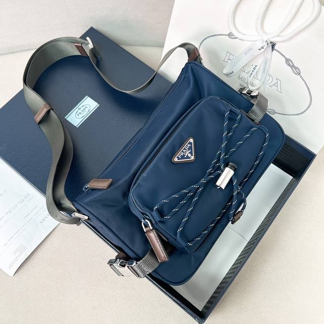 新款邮差包2Vh192新品 这款单肩包兼顾了功能性和装饰性，融合了都市风格和户外元素。Re-Nylon包袋设计轻巧紧凑，融入了丰富的技术细节，赋予配饰现代的运动