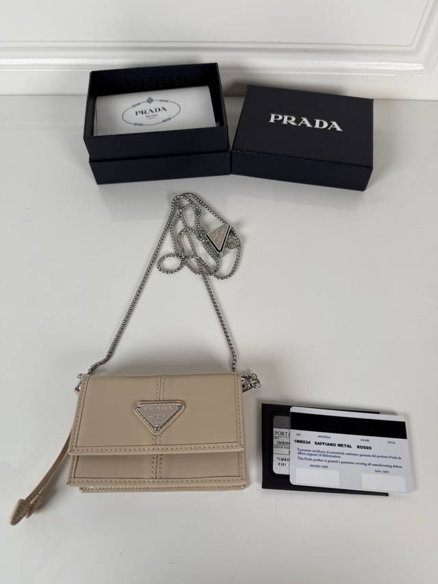 p家女士多功能迷你小背包，型号1Mr034，翻盖式卡夹搭配可拆卸的Saffiano皮革肩带，金属三角形微标装点正面，尺寸11.5 X8 X2.5Cm，内设两个卡