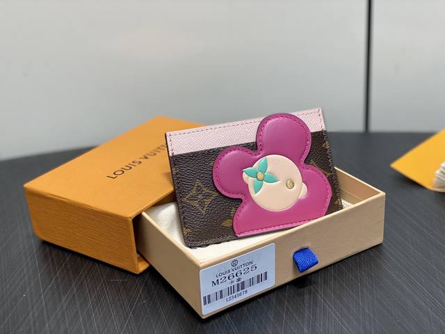 原单精品 M26625老花 圣诞款卡包钱包 本款 Vivienne 卡夹 为 Monogram 帆布顶部融入柔和皮革饰边，以清新色调演绎品牌吉祥物的萌趣形象，成