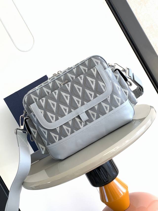 背景原厂 。这款 Dior Hit The Road 信使包是本季新品，将现代风格与 Dior 的高订精神融为一体。采用迪奥黑Cd Diamond 图案帆布和光