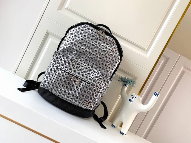 Issey Miyake Bao Bao 经典kuro系列休闲背包质感柔韧的小三角片，采用轻薄硅胶材质，摒弃了传统背包的厚重感，加上网状背带设计，舒适透气，轻巧
