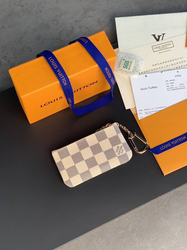 顶级原厂 N62659 白格！这款钱包让不由然想起阳光海滩的悠然，设有钥匙扣，可轻易紧扣到大部分路易威登手袋均设有的 D形环上，日常佩带，漂亮又实用。尺寸：12