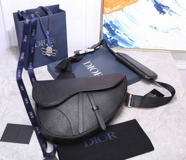 Dior 型号93323大号 镂空皮马鞍包于本季推陈出新，以大号款式呈现，更加实用。采用别致的黑色 Oblique Galaxy 印花效果皮革制作，镂空的光滑牛