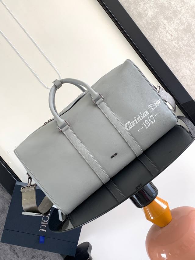 这款 Dior Lingot 50 手袋是本季新款主打单品，实用优雅，别具一格。采用迪奥灰粒面牛皮革精心制作，正面饰以“Christian Dior 1947”