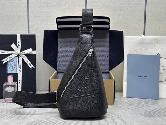 新款胸包荔枝纹2Vz098 这款简约包袋的风格介于双肩包和单肩包之间，颇具混搭特色，彰显p家二元性。包身设计为鹿皮纹牛皮，廓形和功能性，营造出顽趣而新颖的组合。