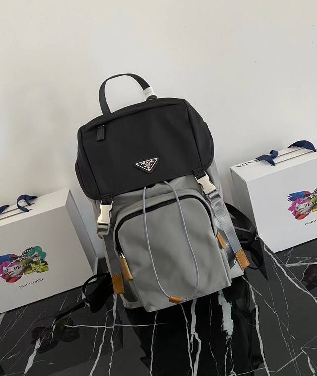 独家首发2Vz135黑灰双肩背包最新配色这款尼龙背包饰有saffiano皮革饰边，用创意与科技打造别致格调。顶级拉丝五金多个口袋和科技材质加衬背面颇具设计特色。