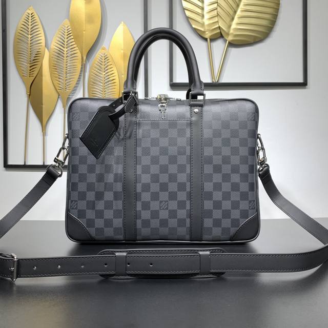 款号：N40445 本款 Voyage 小号公文包取材 Damier Graphite 涂层帆布，搭配皮革侧带、加固包角、顶部手柄和名牌。外袋便于存放智能手机，